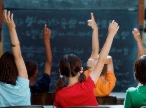 elementary_school_kids_raise_hand_in_class_4x3